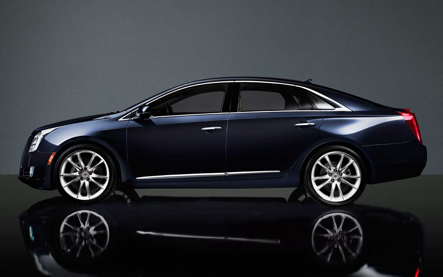 Dark navy blue Cadillac sedan, side view — chrome trim and silver multi-spoke wheels